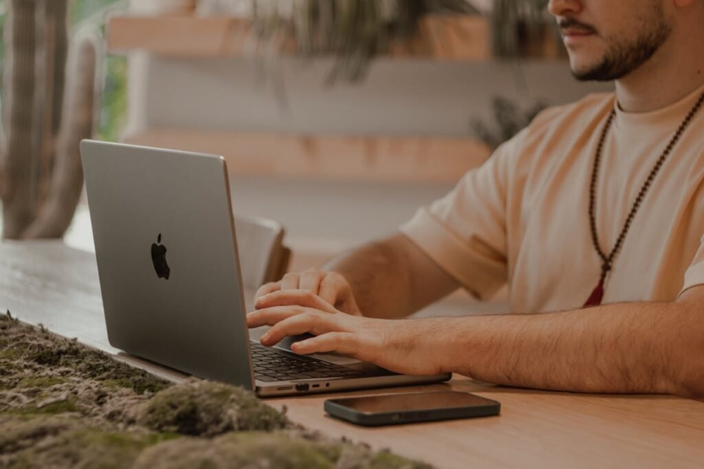 Focused man typing on a laptop in a stylish home office setting with natural decor.